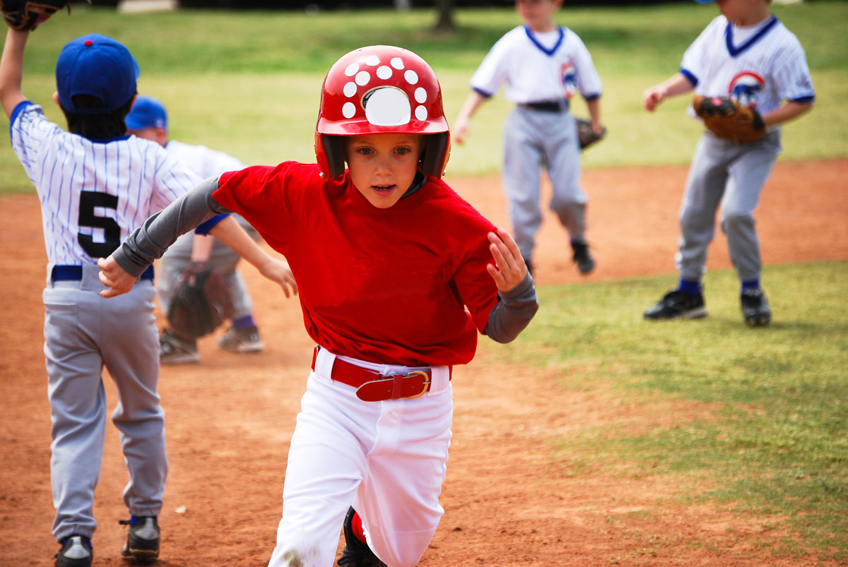 young child in red baseball outfit running the bases