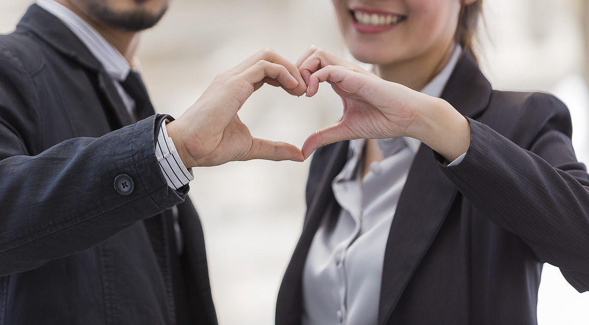 Two business people making a heart by putting both of their hands side by side