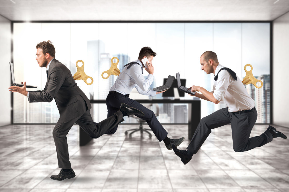 Business people running around the office with winding keys on their backs in a frantic mood